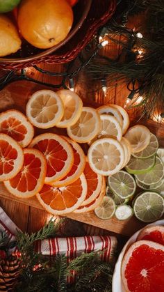 oranges, lemons and limes are arranged on a cutting board next to christmas decorations