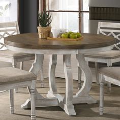 a dining room table with chairs and a bowl of fruit on top of the table