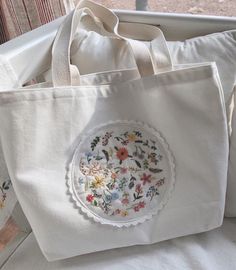 a white tote bag sitting on top of a window sill next to pillows