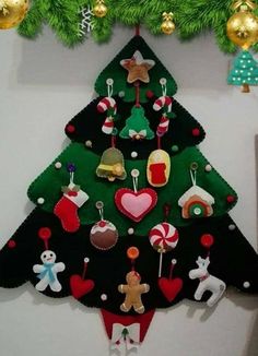 a christmas tree made out of felt with ornaments hanging from it's sides on a wall