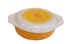 an orange and white bowl with a yellow flower on the top is sitting in front of a white background