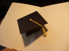 a black graduation cap on top of a white book with a yellow tassel in the middle