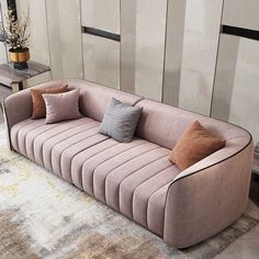 a couch with several pillows on it in front of a rug and wall behind it