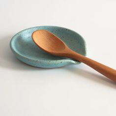 two wooden spoons sitting on top of a blue ceramic bowl with a wood handle