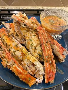 cooked crab legs on a blue plate with dipping sauce