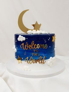 a blue cake with gold stars and the words welcome to the world on it