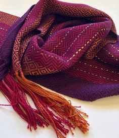 a purple and red scarf laying on top of a white table