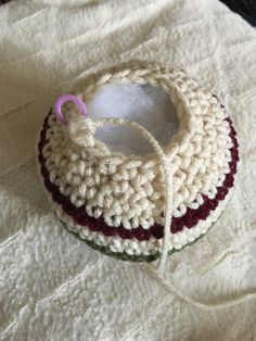 a crocheted basket with a pink handle on top of a white cloth covered table