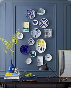 a blue room with plates on the wall and a vase filled with flowers next to it