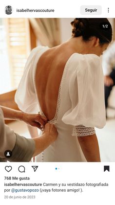 the back of a woman's wedding dress is being fitted with lace and buttons