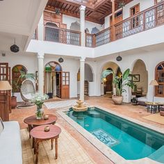 an indoor swimming pool in the middle of a living room with furniture and potted plants