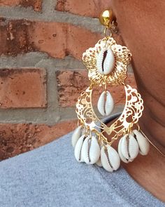 These are unique  Handmade and one of a kind  none other like these   Cowrie shell chandelier style Comfortable Clip on closure  gold metal with hand applied cowrie shells  They hang 3.5 inches  Medium Large sized These are very lightweight on the ear Easy to wear They are one of a kind These Earrings are a classic and timeless addition to any  afrocentric wardrobe Handmade Gold Chandelier Earrings For Summer, Bohemian Gold Chandelier Earrings For Beach, Gold Bohemian Chandelier Earrings For The Beach, Gold Bohemian Shell For Festival, Gold Cowrie Shell Earrings For Gift, Gold Cowrie Shell Earrings As Gift, Handmade Bohemian Gold Shell, Handmade Gold Bohemian Shell, Unique Gold Shell Earrings