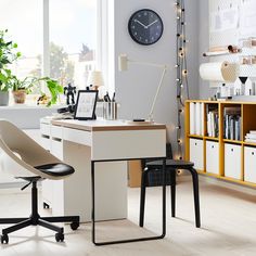 a desk with a clock on the wall above it and a chair next to it