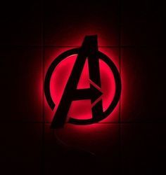 the avengers logo is lit up against a dark background with red light in the center