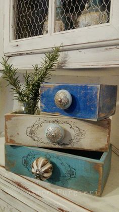 three wooden boxes with knobs and handles on top of a white dresser next to a potted plant