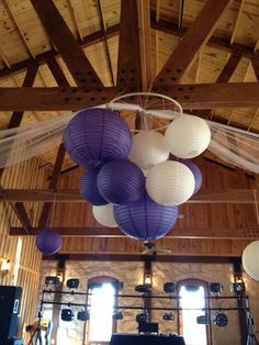 several purple and white lanterns hanging from the ceiling in a large room with wooden beams