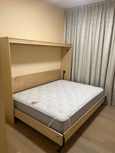 a bed with a wooden headboard in a room next to a curtained window