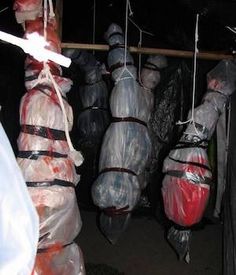 several bags are wrapped in plastic and hanging from the ceiling