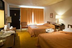 two beds in a hotel room with orange curtains