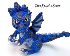 a crocheted blue and gray dragon figurine sitting on top of a white surface