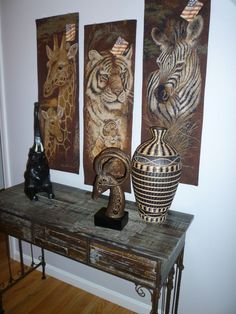 three vases are sitting on a table with paintings behind them and an animal statue