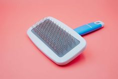 a blue and white brush sitting on top of a pink surface