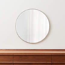 a round mirror on the wall above a dresser