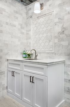 a white bathroom with marble tile on the walls