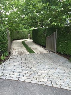 a driveway with a brick walkway and gate