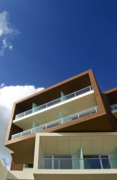 an apartment building with balconies and balconyes against a blue sky filled with clouds