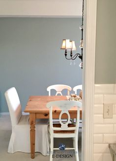 a dining room table with white chairs and a chandelier