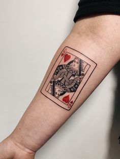 a person with a tattoo on their arm holding a playing card