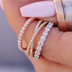 a woman's hand holding three rings with diamonds on them and one ring in the middle