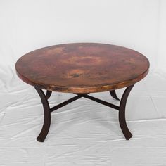 an old round table with metal legs on a white background in front of a white backdrop