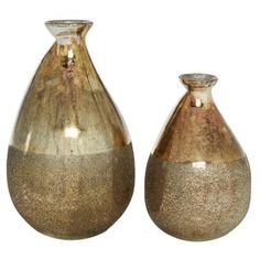 two metallic vases sitting next to each other on a white surface with gold flecking