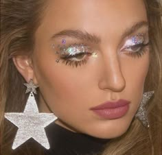 a close up of a woman with glitter on her face and star shaped earring