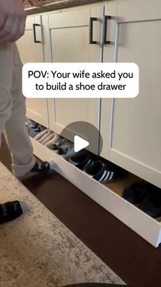 a person standing in front of a kitchen counter with shoes on the floor and an open shoe drawer