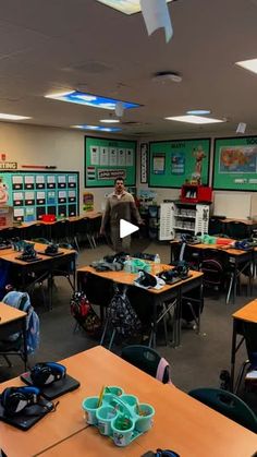 a classroom with many desks and people in the back ground looking at pictures on the wall