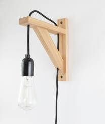 a light that is on the wall with a wooden frame and black cord attached to it