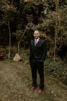 a man standing in the grass wearing a suit and tie