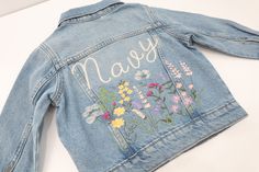 Embroidered Denim Jacket With Wildflowers! Name will be done in blonde thread in chain font.  Color Wildflowers  Old Navy Jackets *Runs small in my opinion Select Size: Toddler Light Denim Jacket 100% Cotton 3-6 months 6-12 months 12-18 months 2T 3T 4T 5T Girls Medium Denim Jackets 95% Cotton, 5% Spandex  S (6/7) M (8) L (10/12) XL (14/16) Order a matching mama jacket!  https://thebohoglam.etsy.com/listing/1701260875 Spring Blue Denim Jacket With Custom Embroidery, Picture Walls, Light Denim Jacket, Kids Jackets, Embroidered Denim Jacket, Jacket Denim, Navy Jackets, Embroidered Denim, Denim Jackets