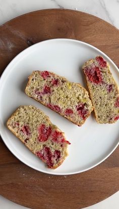 three slices of strawberry bread on a white plate with a wooden cutting board behind it