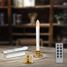 a white candle sitting on top of a table next to two remotes and a pen