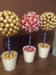 three small white buckets filled with candy and gold foil wrapped candies in them