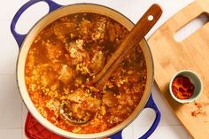 a pot filled with stew next to a cutting board