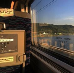 a view from inside a train looking out the window at water and hills in the distance