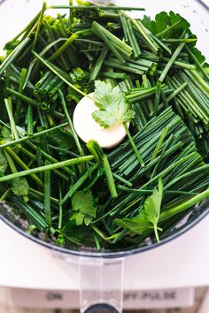 green vegetables are in a food processor ready to be mixed with other foodstuffs