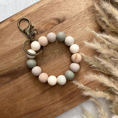 a wooden board with a keychain that has some beads and a baseball on it