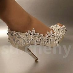 a woman's white wedding shoe with flowers on the side and heels that are very high