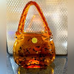 an orange handbag sitting on top of a glass table next to a white wall